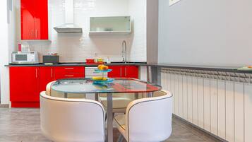 Una cocina moderna con armarios rojos, una mesa de vidrio y sillas blancas.