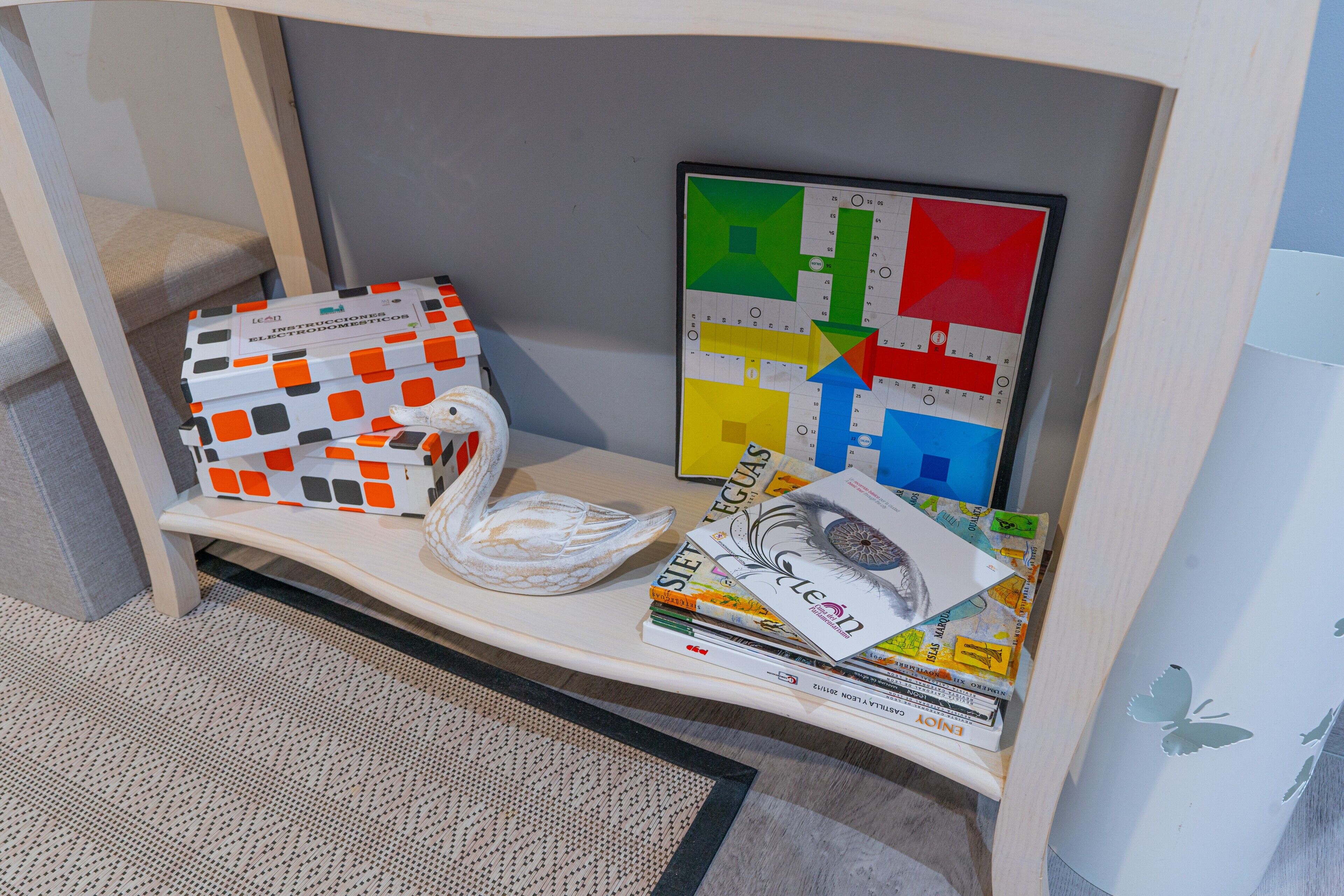 Uno scaffale con libri, un cigno decorativo e un tavolino da puzzle.