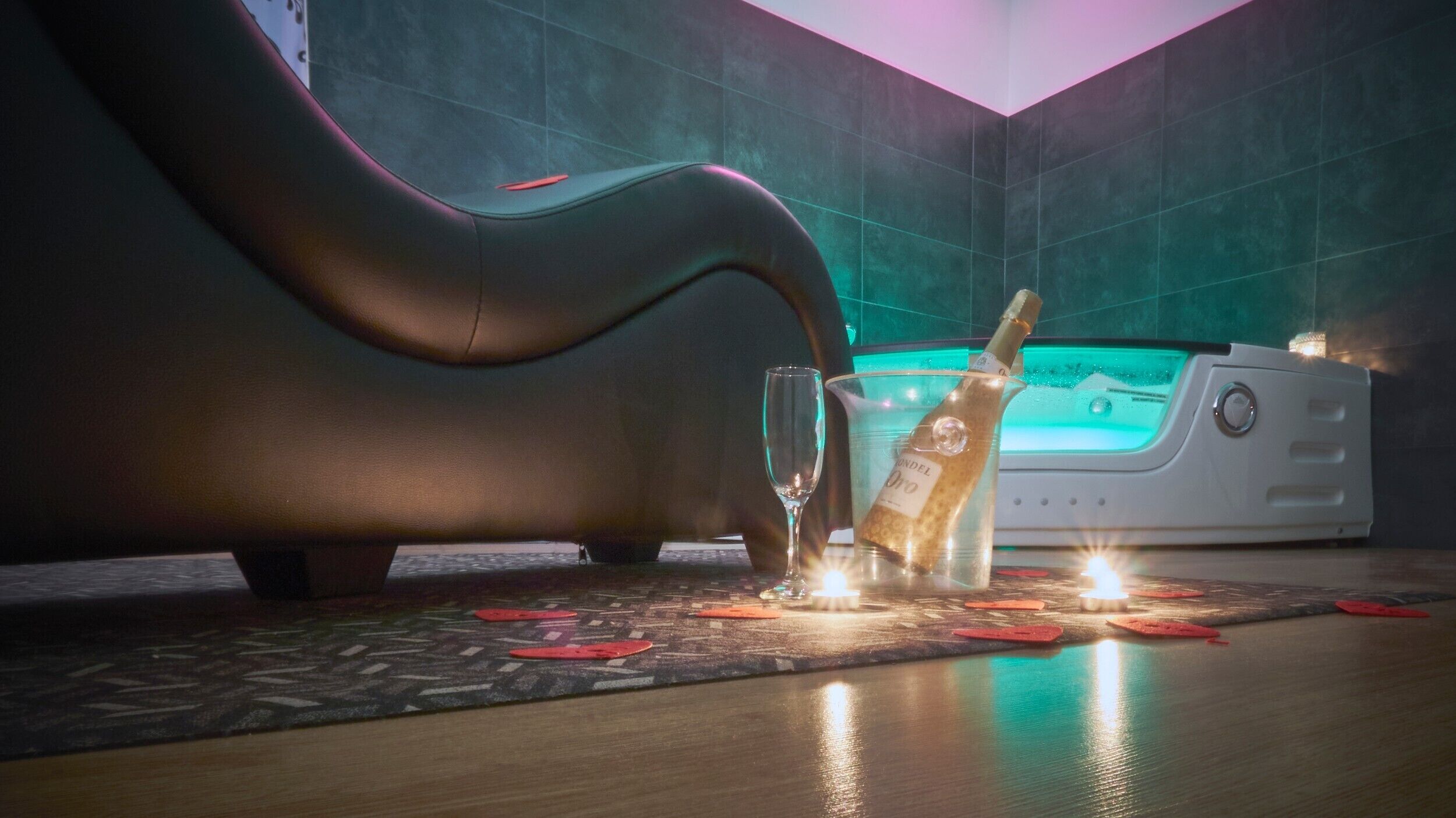 Een massagestoel, een fles champagne en een kleine tafel met kaarsen in een spa.