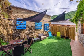 A patio with outdoor furniture, a table with cups and a book, and a wooden fence.