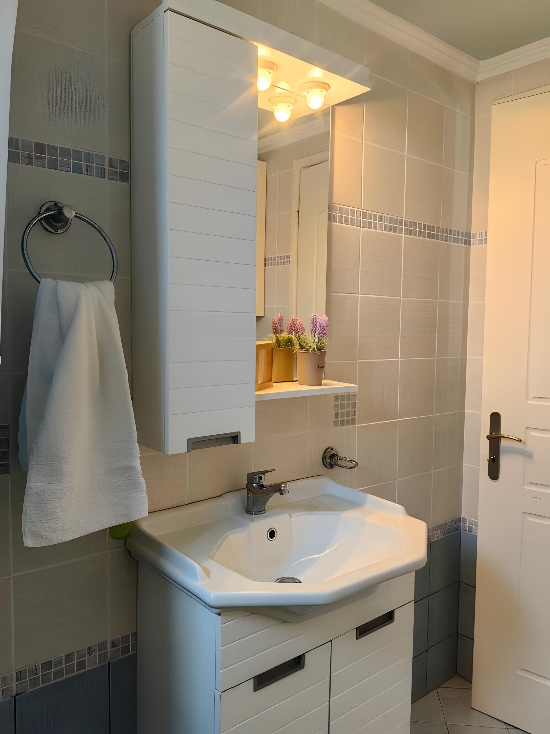 A bathroom with a white sink, a mirror, a towel rack, and a door.