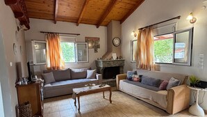 A spacious living room with a fireplace, two sofas, a coffee table, and a wooden ceiling.