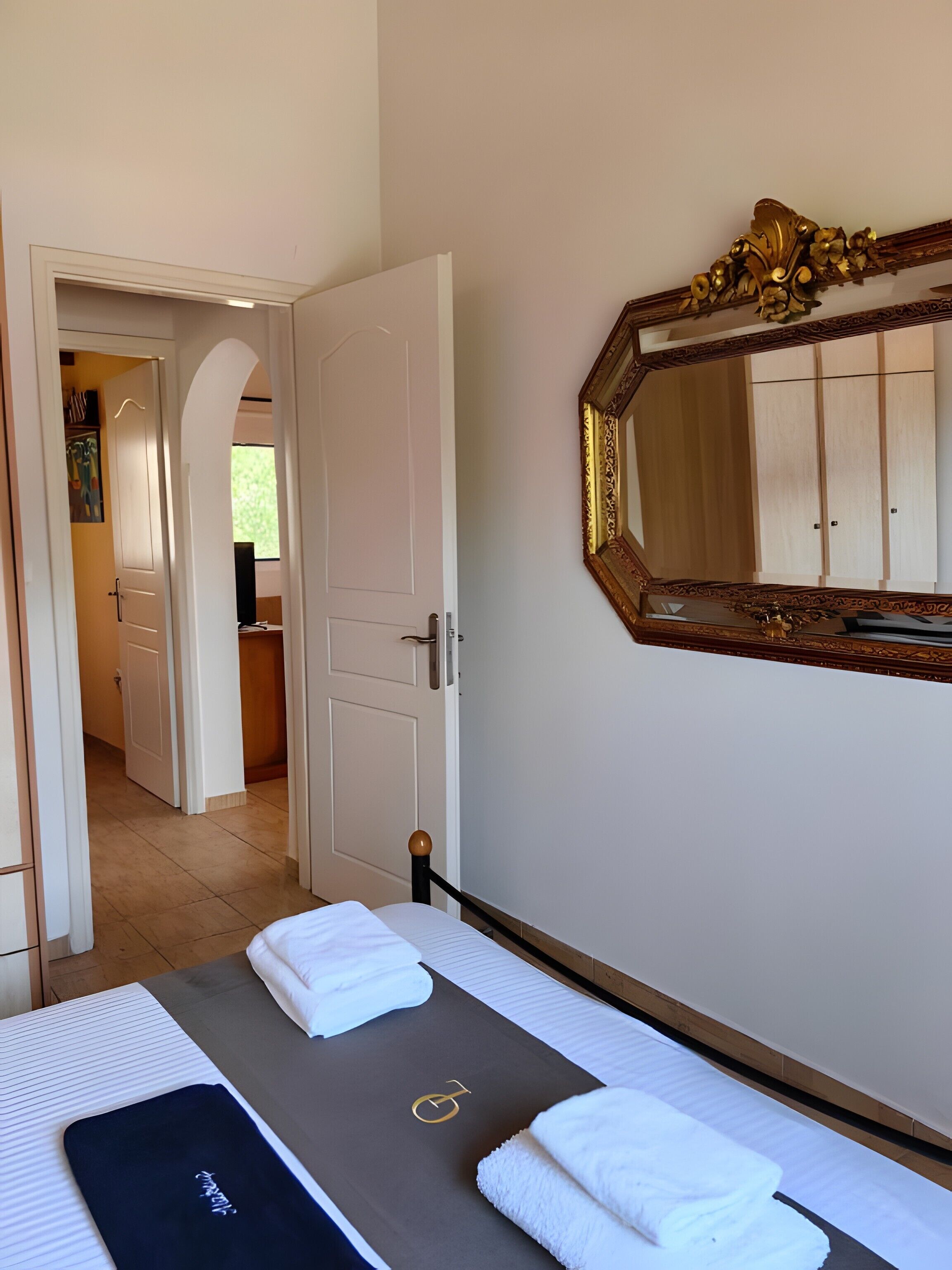 Ein Hotelzimmer mit Bett, einem großen Spiegel und Blick auf den Flur.