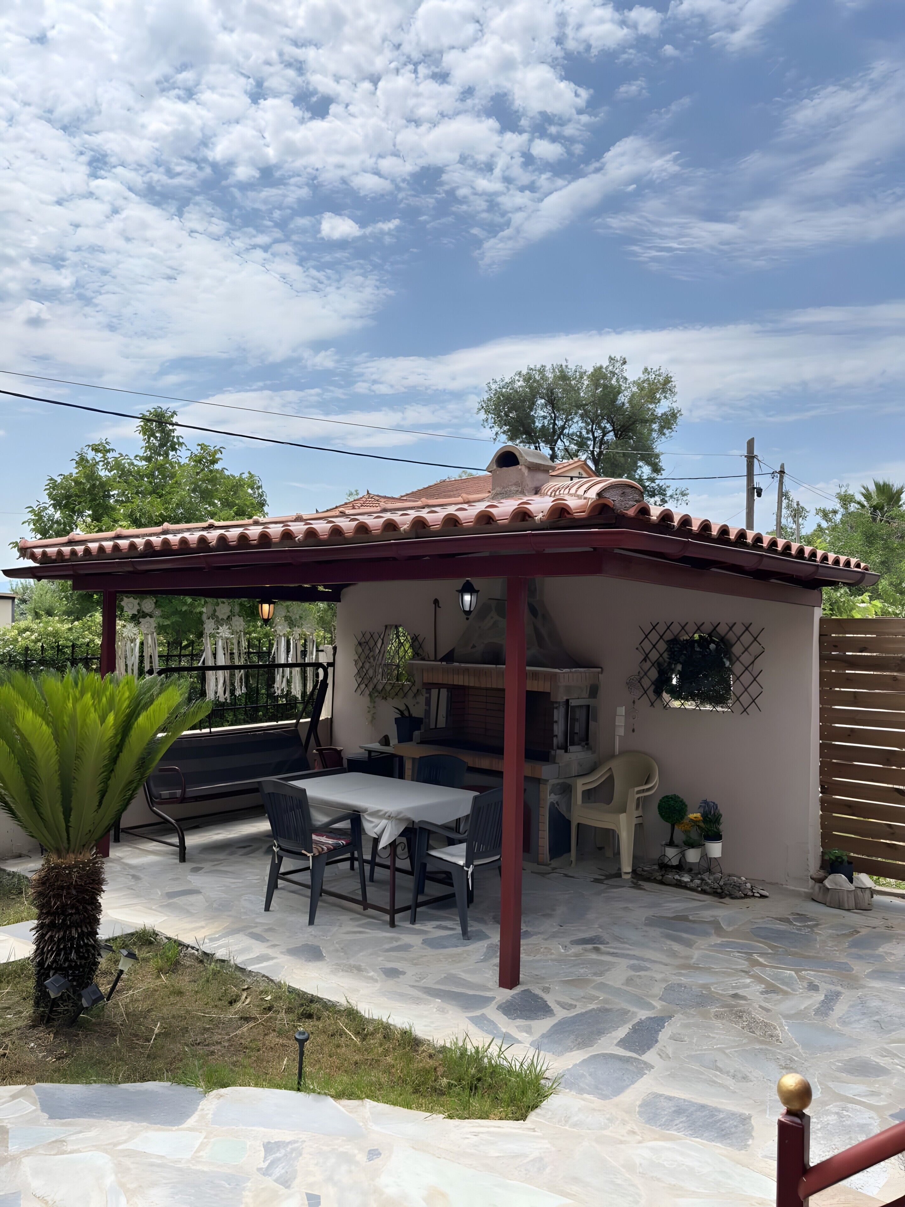 Un patio con tavolo e sedie, un pergolato e un pavimento in pietra.