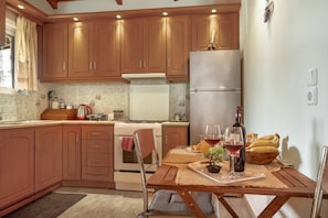 Une cuisine avec des meubles de rangement en bois, un réfrigérateur, une table à manger avec des sets de table et une petite plante en pot.
