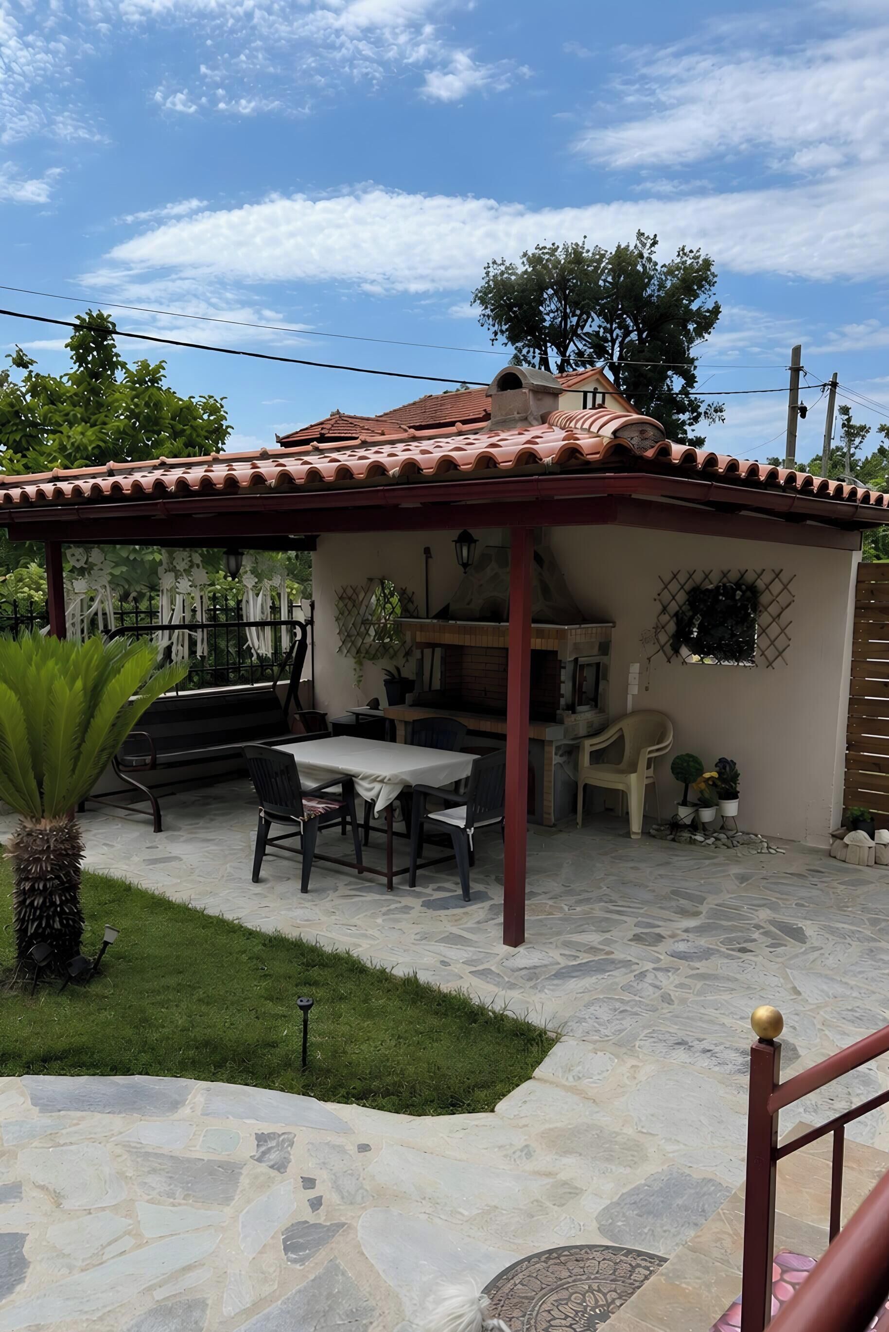 A patio with a grill, outdoor seating, and a pergola.