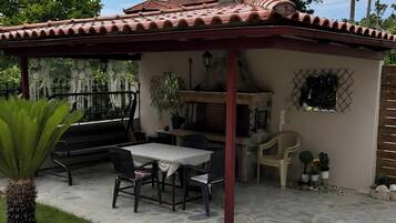 A patio with a grill, outdoor seating, and a pergola.
