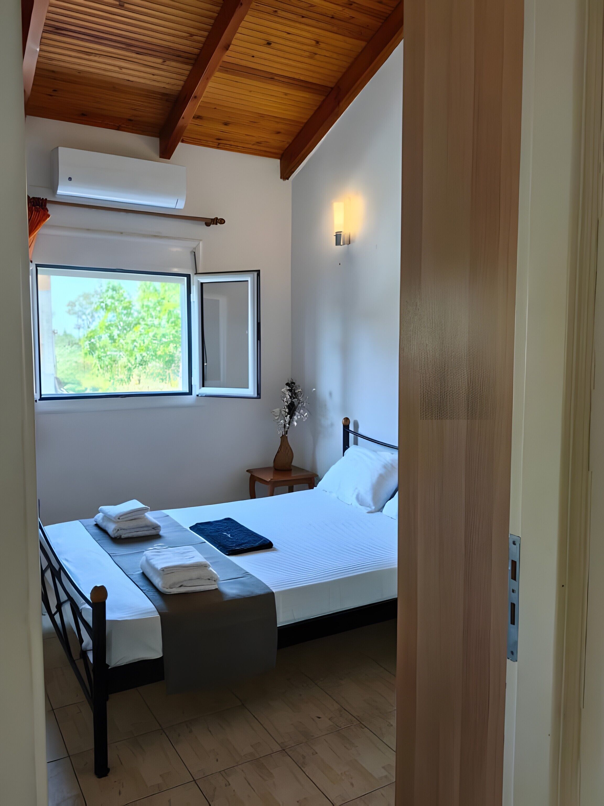 Ein Schlafzimmer mit einem Bett, einem Nachttisch, einem Fenster und einem Deckenventilator.