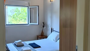 A bedroom with a bed, a nightstand, a window, and a ceiling fan.