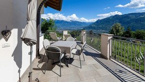 Un balcón con una mesa y sillas, una sombrilla y vistas a las montañas.
