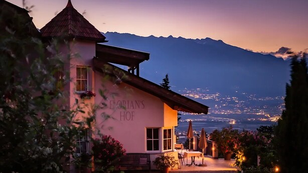 Un edificio con un cartel que dice 'Georgian's Hof', con vistas a montañas y luces a lo lejos.