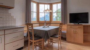 Una habitación con una mesa de comedor, sillas, un televisor y una ventana con vistas.