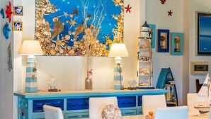 A dining area with a blue cabinet, white chairs, and a wall decorated with seashells and starfish. - Holiday Home 'Villa Tiziana' with Sea View, Wi-Fi and Air Conditioning (Costa Rei)