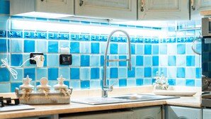 A kitchen with a blue-tiled backsplash, a stainless steel sink, and a countertop with a dish rack and jars. - Holiday Home 'Villa Tiziana' with Sea View, Wi-Fi and Air Conditioning (Costa Rei)