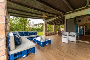 An outdoor patio with a blue and white seating area, a small table, and a covered entrance.