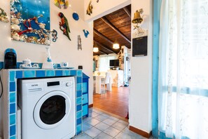 A laundry area with a washing machine, a blue cabinet, and a wall decorated with seashells and fish.
