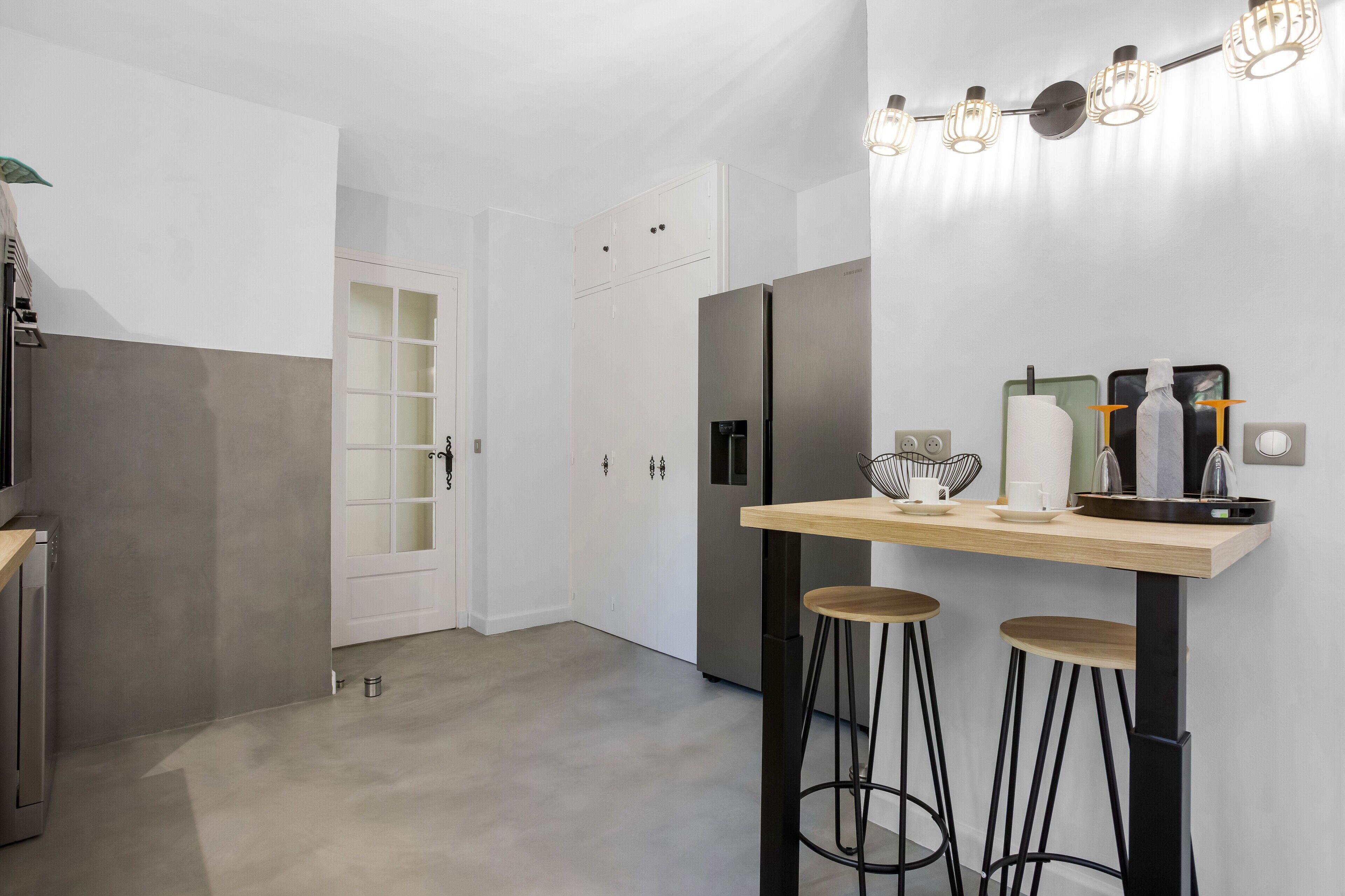 Eine moderne Küche mit einem Edelstahlkühlschrank, einer Holztresenplatte und Barhocker.