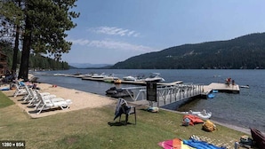 A lakeside dock with boats, lounge chairs, and a small wooden structure.