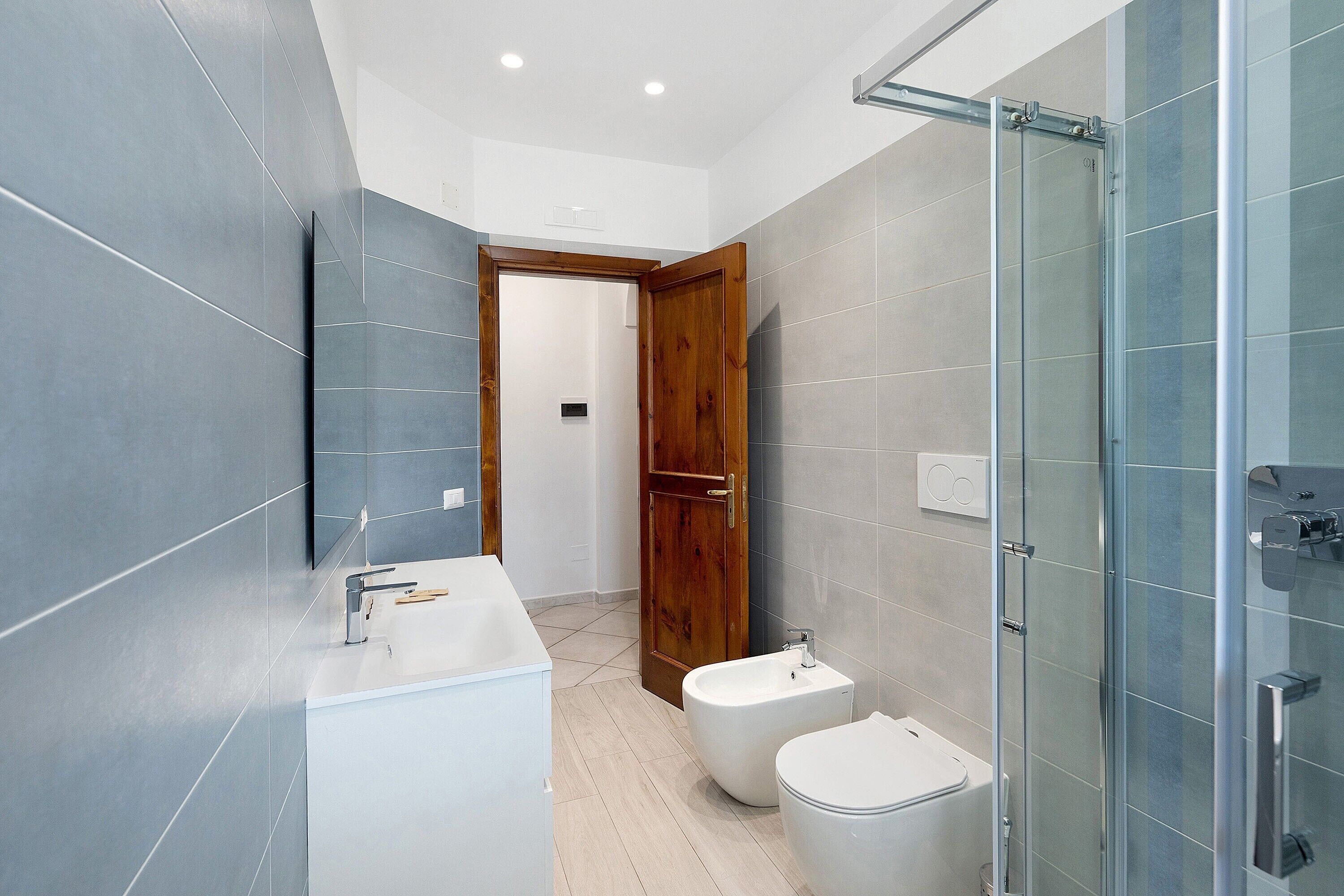 A modern bathroom with a shower, toilet, bidet, and a sink.