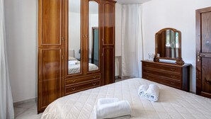A bedroom with a large wardrobe, a bed with rolled towels, and a dresser with a mirror. - Apartment 'Appartamento Capri' with Sea View, Wi-Fi and Air Conditioning (Massa Lubrense)