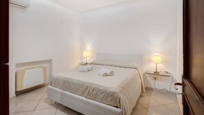 Een slaapkamer met een bed, nachtlampjes, een radiator en een deur.