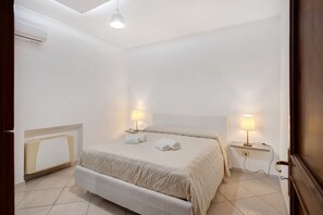 Une chambre à coucher avec un lit, des lampes de chevet, un radiateur et une porte.