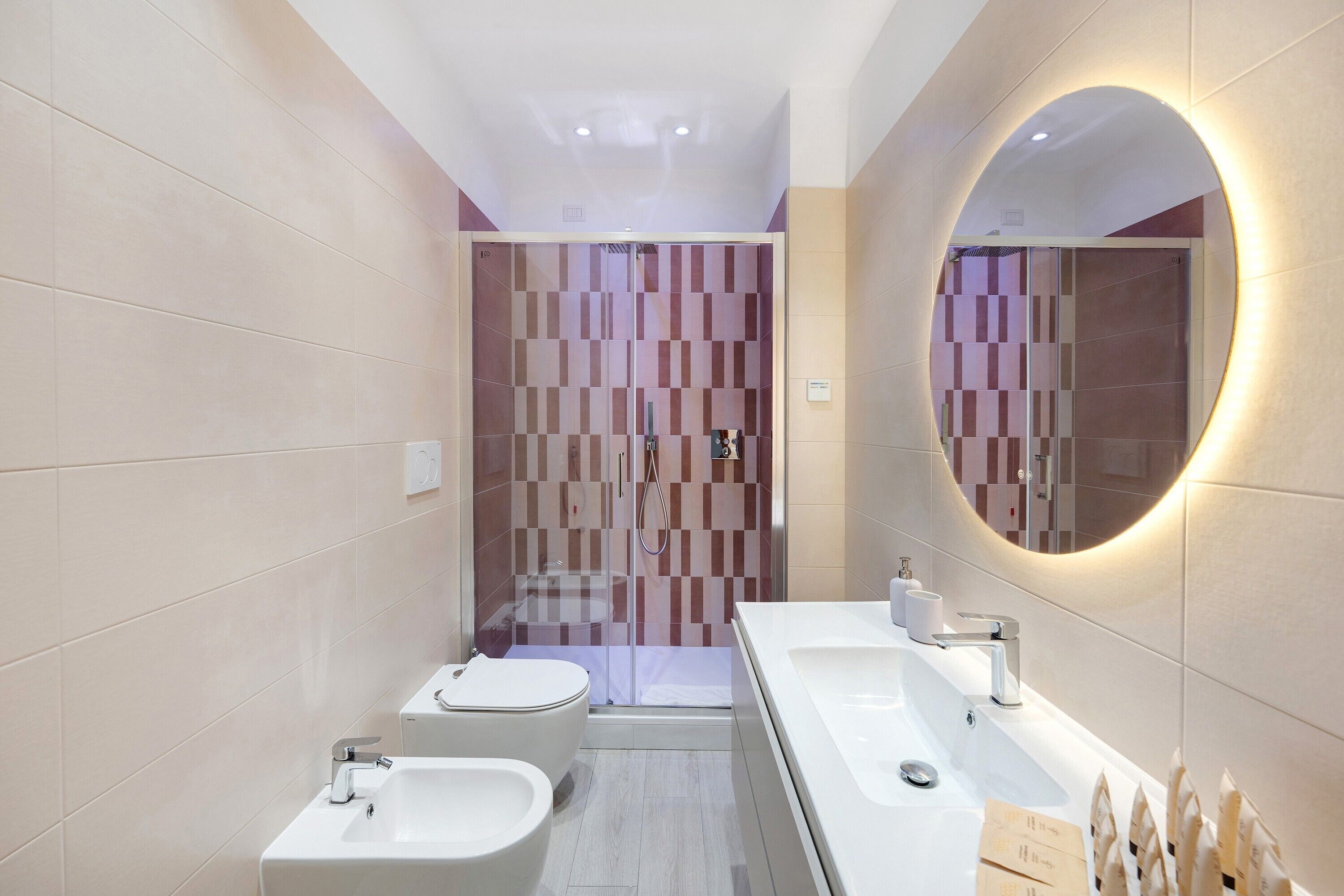 A modern bathroom with a shower, two sinks, and a toilet.