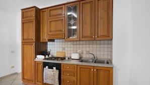 Een keuken met houten kastjes, een gasfornuis, een spoelbak en een betegelde achterwand.
