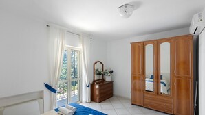 Ein Hotelzimmer mit Bett, Kleiderschrank, Schminktisch und einem Balkon mit Vorhängen.