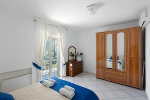 Une chambre d’hôtel comprenant un lit, une armoire, une commode et un balcon avec des rideaux.