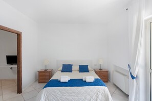 Un dormitorio con cama, dos mesitas de noche, televisión y armario.