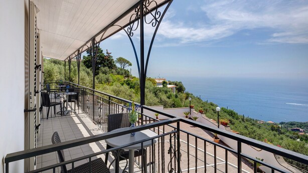 Ein Balkon mit Gartenmöbeln, Meerblick und Geländer.