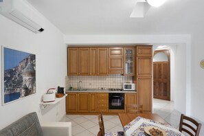 Una cocina con armarios de madera, microondas, pileta y una mesa de comedor con sillas.