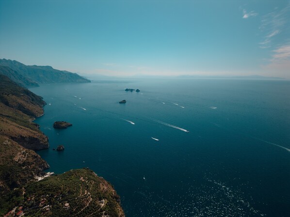 A coastal landscape with a clear view of the sea, rocky terrain, and a few boats. - Apartment 'Appartamento Sorrento' with Sea View, Wi-Fi, and Air Conditioning (Massa Lubrense)