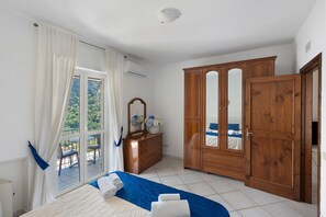 A bedroom with a bed, a dresser, a wardrobe, and a window with curtains. - Apartment 'Appartamento Sorrento' with Sea View, Wi-Fi, and Air Conditioning (Massa Lubrense)