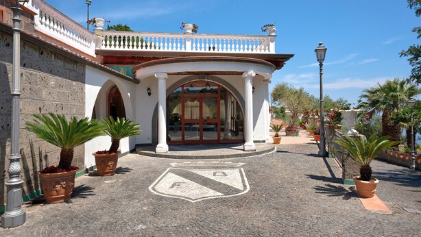 A building with a white facade, arched entrance, and a cobblestone pathway. - Apartment 'Appartamento Napoli' with Sea View, Wi-Fi and Air Conditioning (Massa Lubrense)