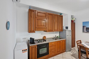 Une cuisine compacte avec des meubles en bois, une cuisinière à gaz, un four encastré, un four à micro-ondes et un réfrigérateur.