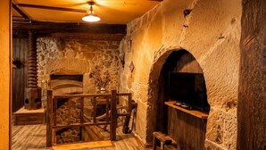 A stone-walled room with a fireplace, wooden furniture, and a television mounted on the wall.