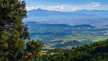 Vista panorámica de un paisaje montañoso con zonas boscosas y colinas distantes.