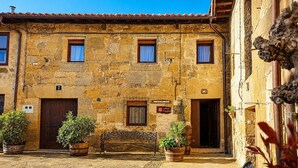 A stone building with a bench, potted plants, and a sign indicating a restaurant.