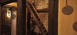 Una escalera de madera con paredes de piedra, barandilla de metal y decoración de cuerda.