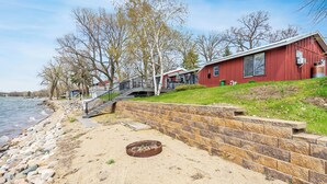 A waterfront property with a red building, stone steps, and a grassy area. - Ottertail Lakefront 3BR. Boat lift. Cozy. Awesome! (Ottertail)