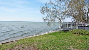 A waterfront park with a grassy area, a wooden walkway, and a metal railing overlooking the water. - Ottertail Lakefront 3BR. Boat lift. Cozy. Awesome! (Ottertail)