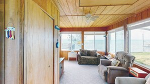 A cozy cabin with a wooden interior, a ceiling fan, a view of the lake, and a dining area with a table and chairs. - Ottertail Lakefront 3BR. Boat lift. Cozy. Awesome! (Ottertail)