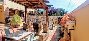 An outdoor patio with tables and chairs, potted plants, and a pergola structure.