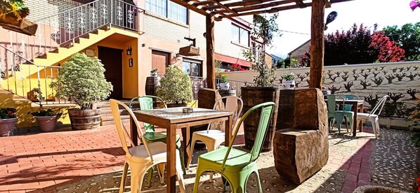 An outdoor patio with a table and chairs, potted plants, and a staircase leading to a building. - Apartment 'El Guardaviñas Periquita' with Mountain View, Shared Terrace and Wi-Fi (ABALOS)