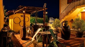 Een terras buiten, met een pergola, zitplaatsen en potplanten.