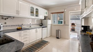 Une cuisine moderne avec des meubles blancs, une poubelle en acier inoxydable et une fenêtre donnant sur un beau paysage.