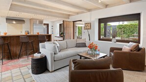 A modern living room with a sofa, two armchairs, a coffee table, and a kitchen area with bar stools. - Luxurious Garden Home Walking Distance to Downtown SB (Santa Barbara)