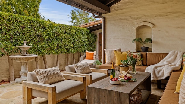 A cozy outdoor seating area with a stone fountain, wooden furniture, and a potted plant. - Luxurious Garden Home Walking Distance to Downtown SB (Santa Barbara)